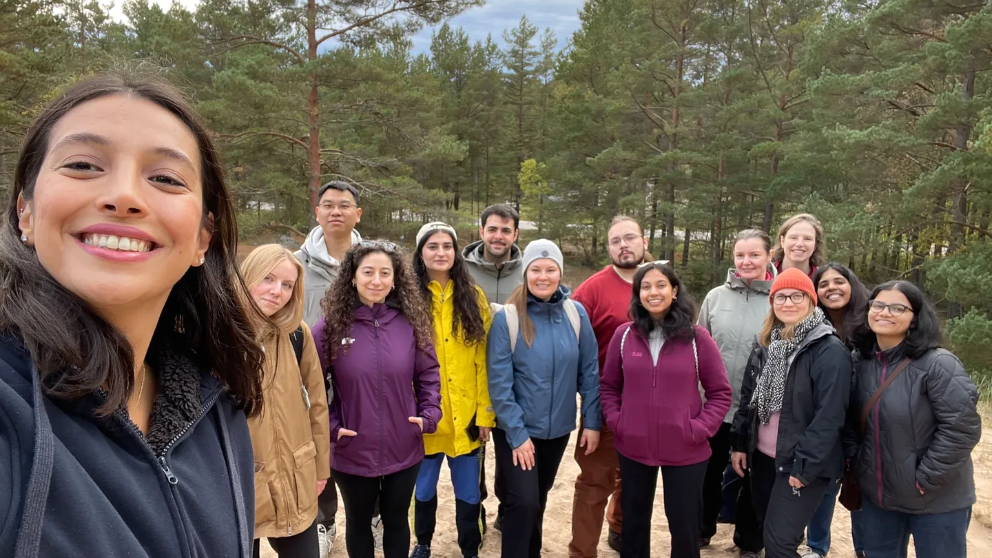 A group selfie on a woodland path, with pine trees in the background.
